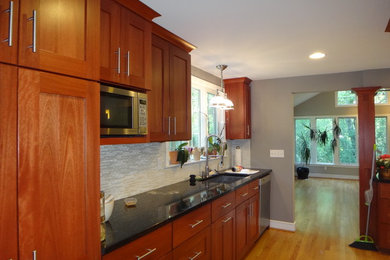 Inspiration for a mid-sized transitional l-shaped light wood floor and brown floor open concept kitchen remodel in New York with an undermount sink, shaker cabinets, medium tone wood cabinets, matchstick tile backsplash, stainless steel appliances, an island, quartz countertops and gray backsplash