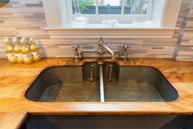 Small farmhouse l-shaped medium tone wood floor and brown floor enclosed kitchen photo in Boston with an undermount sink, glass-front cabinets, wood countertops, porcelain backsplash, no island, brown countertops, blue backsplash, stainless steel appliances and blue cabinets