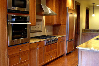 Eat-in kitchen - galley dark wood floor eat-in kitchen idea in Denver with a drop-in sink, medium tone wood cabinets, granite countertops, stainless steel appliances and an island