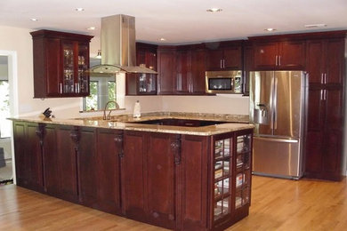 Mid-sized transitional u-shaped light wood floor and beige floor enclosed kitchen photo in Baltimore with an undermount sink, shaker cabinets, dark wood cabinets, granite countertops, stainless steel appliances and a peninsula