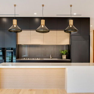 Design ideas for a large contemporary galley kitchen in Adelaide with an integrated sink, flat-panel cabinets, black cabinets, grey splashback, glass sheet splashback, panelled appliances, with island, beige floor and beige benchtop.