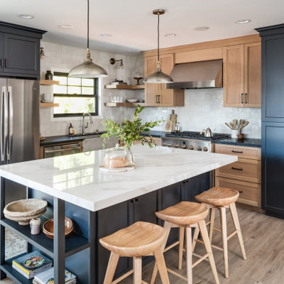 Kitchen - mid-sized transitional l-shaped vinyl floor and beige floor kitchen idea in San Diego with a farmhouse sink, shaker cabinets, solid surface countertops, white backsplash, terra-cotta backsplash, black appliances, an island, black countertops and gray cabinets
