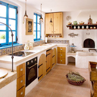 Photo of a small mediterranean u-shaped eat-in kitchen in Other with an integrated sink, open cabinets, medium wood cabinets, limestone benchtops, multi-coloured splashback, ceramic splashback, white appliances, brick floors and no island.