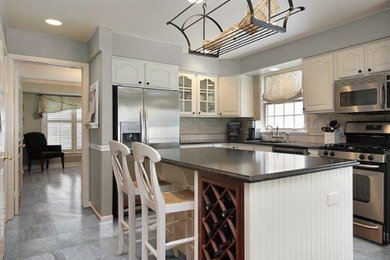 Exempel på ett avskilt, stort klassiskt l-kök, med en nedsänkt diskho, luckor med profilerade fronter, vita skåp, granitbänkskiva, beige stänkskydd, stänkskydd i stenkakel, rostfria vitvaror, klinkergolv i porslin, en köksö och grått golv