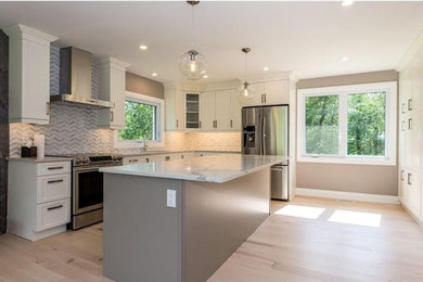 Enclosed kitchen - large contemporary l-shaped light wood floor and brown floor enclosed kitchen idea in Ottawa with shaker cabinets, white cabinets, quartz countertops, gray backsplash, marble backsplash, an island, a double-bowl sink, stainless steel appliances and white countertops