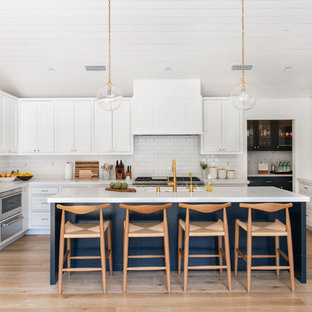 Large transitional kitchen appliance - Example of a large transitional l-shaped medium tone wood floor and brown floor kitchen design in Los Angeles with a single-bowl sink, shaker cabinets, white cabinets, quartz countertops, white backsplash, ceramic backsplash, stainless steel appliances, an island and white countertops