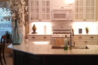 Example of a mid-sized transitional l-shaped ceramic tile and white floor eat-in kitchen design in Houston with a farmhouse sink, raised-panel cabinets, white cabinets, quartz countertops, white backsplash, subway tile backsplash, an island and white appliances