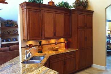 Inspiration for a mid-sized timeless u-shaped travertine floor eat-in kitchen remodel in Orlando with a double-bowl sink, raised-panel cabinets, medium tone wood cabinets, granite countertops, beige backsplash, ceramic backsplash, stainless steel appliances and a peninsula