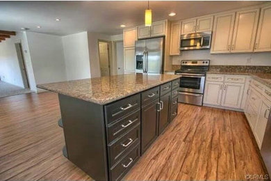 Inspiration for a large contemporary l-shaped dark wood floor open concept kitchen remodel in Other with an undermount sink, beaded inset cabinets, beige cabinets, granite countertops, stainless steel appliances and an island