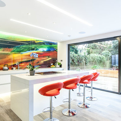 Inspiration for a contemporary porcelain tile eat-in kitchen remodel in London with an undermount sink, flat-panel cabinets, white cabinets, quartz countertops, glass sheet backsplash, an island and multicolored backsplash