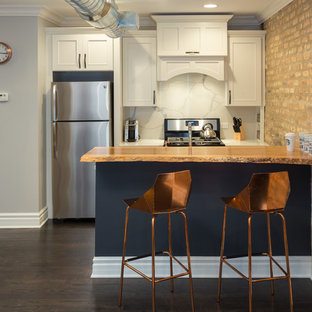 Imagen de cocina de galera, clásica renovada, de tamaño medio, abierta, con fregadero bajoencimera, puertas de armario blancas, encimera de madera, salpicadero blanco, salpicadero de mármol, electrodomésticos de acero inoxidable, suelo de madera oscura, una isla, suelo marrón y armarios estilo shaker