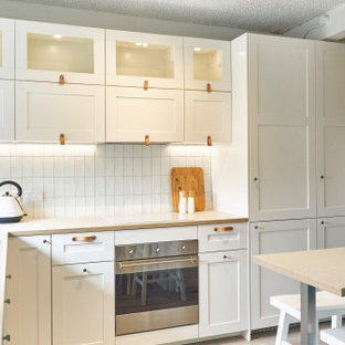 Inspiration for a small beach style l-shaped kitchen pantry in Melbourne with a farmhouse sink, shaker cabinets, white cabinets, laminate benchtops, white splashback, ceramic splashback, stainless steel appliances, vinyl floors, a peninsula, grey floor and beige benchtop.