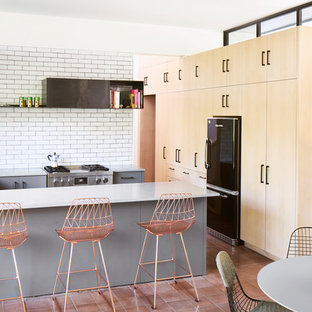 This is an example of a contemporary l-shaped open plan kitchen in Austin with an undermount sink, flat-panel cabinets, light wood cabinets, white splashback, subway tile splashback, stainless steel appliances, terra-cotta floors, a peninsula and pink floor.
