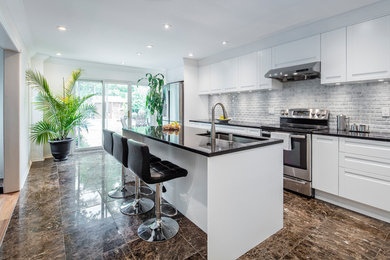 Example of a mid-sized trendy single-wall marble floor eat-in kitchen design in Toronto with flat-panel cabinets, white cabinets, an island, a single-bowl sink, granite countertops, gray backsplash, marble backsplash and stainless steel appliances