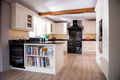 Ejemplo de cocina de estilo de casa de campo de tamaño medio con fregadero sobremueble, armarios con paneles con relieve, encimera de granito y electrodomésticos negros
