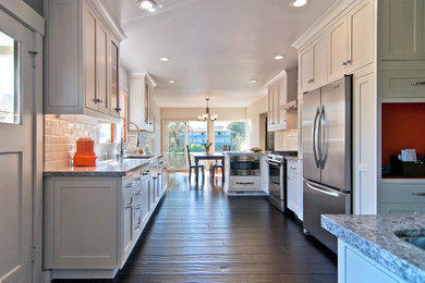 Example of a mid-sized transitional l-shaped dark wood floor eat-in kitchen design in San Francisco with white cabinets, no island, an undermount sink, shaker cabinets, granite countertops, white backsplash, ceramic backsplash and stainless steel appliances