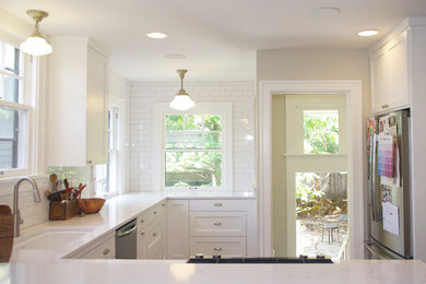 Eat-in kitchen - mid-sized craftsman u-shaped light wood floor eat-in kitchen idea in Portland with an undermount sink, shaker cabinets, white cabinets, solid surface countertops, white backsplash, porcelain backsplash, stainless steel appliances, a peninsula and white countertops