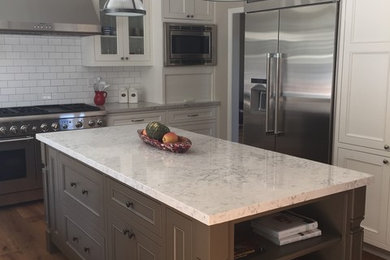 Example of a large transitional u-shaped medium tone wood floor eat-in kitchen design in San Francisco with recessed-panel cabinets, white cabinets, white backsplash, subway tile backsplash, stainless steel appliances and an island