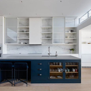 Design ideas for a large modern l-shaped open plan kitchen in San Francisco with an undermount sink, open cabinets, white cabinets, quartz benchtops, white splashback, stone slab splashback, stainless steel appliances, light hardwood floors, with island and beige floor.