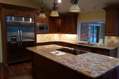 Example of a classic l-shaped eat-in kitchen design in Orlando with an undermount sink, recessed-panel cabinets, medium tone wood cabinets, granite countertops, beige backsplash, stone tile backsplash and stainless steel appliances