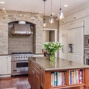 This is an example of a large traditional u-shaped separate kitchen in Other with a double-bowl sink, raised-panel cabinets, white cabinets, grey splashback, glass tile splashback, stainless steel appliances, quartzite benchtops, medium hardwood floors and with island.