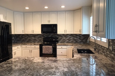 Mid-sized trendy u-shaped medium tone wood floor and brown floor eat-in kitchen photo in Denver with an undermount sink, raised-panel cabinets, white cabinets, granite countertops, metallic backsplash, metal backsplash, black appliances and a peninsula