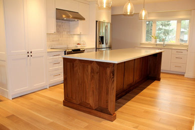 Exempel på ett stort modernt linjärt kök och matrum, med en undermonterad diskho, skåp i shakerstil, vita skåp, bänkskiva i kvarts, vitt stänkskydd, stänkskydd i keramik, rostfria vitvaror, ljust trägolv och en köksö