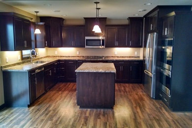 Elegant u-shaped medium tone wood floor eat-in kitchen photo in Minneapolis with an undermount sink, recessed-panel cabinets, dark wood cabinets, granite countertops, stainless steel appliances and an island