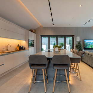 Inspiration for a large contemporary galley open plan kitchen in Cheshire with a submerged sink, flat-panel cabinets, beige cabinets, beige splashback, stainless steel appliances, porcelain flooring, an island, grey floors and grey worktops.