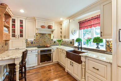 Inspiration for a mid-sized transitional u-shaped medium tone wood floor and brown floor kitchen remodel in DC Metro with an undermount sink, raised-panel cabinets, white cabinets, granite countertops, multicolored backsplash, mosaic tile backsplash, paneled appliances and a peninsula
