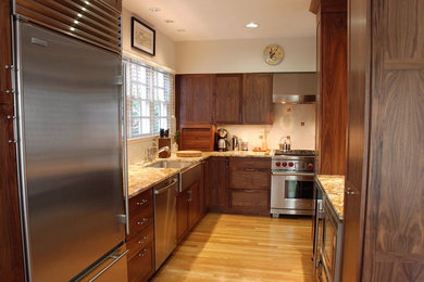 Example of a large classic l-shaped light wood floor open concept kitchen design in DC Metro with shaker cabinets, dark wood cabinets, stainless steel appliances, a farmhouse sink, granite countertops, beige backsplash, stone tile backsplash and an island