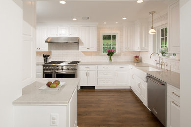 Inspiration for a mid-sized timeless u-shaped medium tone wood floor and brown floor enclosed kitchen remodel in DC Metro with a farmhouse sink, raised-panel cabinets, white cabinets, quartz countertops, gray backsplash, subway tile backsplash, stainless steel appliances and a peninsula