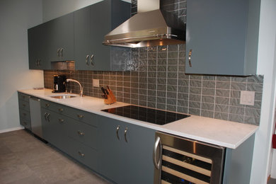 Example of a large mid-century modern l-shaped porcelain tile eat-in kitchen design in DC Metro with flat-panel cabinets, gray backsplash, stainless steel appliances, an undermount sink, blue cabinets, laminate countertops, mosaic tile backsplash and no island