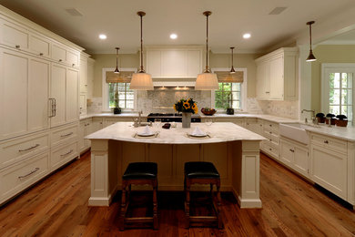 ワシントンD.C.にある高級な広いトランジショナルスタイルのおしゃれなキッチン (エプロンフロントシンク、シェーカースタイル扉のキャビネット、白いキャビネット、大理石カウンター、白いキッチンパネル、モザイクタイルのキッチンパネル、パネルと同色の調理設備、濃色無垢フローリング、茶色い床、白いキッチンカウンター) の写真
