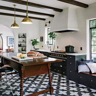 This is an example of a mediterranean kitchen in Portland with shaker cabinets, black cabinets, white splashback, metro tiled splashback, black appliances, an island and ceramic flooring.