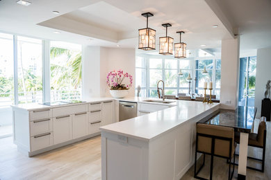 Mid-sized trendy u-shaped light wood floor and beige floor open concept kitchen photo in Miami with recessed-panel cabinets, white cabinets, quartz countertops, a peninsula, a double-bowl sink, white backsplash, stone slab backsplash and stainless steel appliances