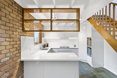 Идея дизайна: п-образная кухня в современном стиле с врезной мойкой, плоскими фасадами, белыми фасадами, белым фартуком, фартуком из плитки кабанчик, полуостровом, синим полом и белой столешницей