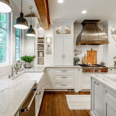 Inspiration for a mid-sized cottage u-shaped dark wood floor and brown floor eat-in kitchen remodel in Atlanta with white cabinets, quartzite countertops, white backsplash, an island, a farmhouse sink, subway tile backsplash, stainless steel appliances, shaker cabinets and white countertops