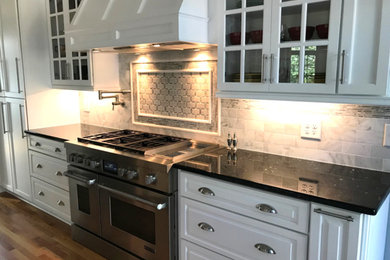 Example of a large transitional l-shaped medium tone wood floor and brown floor open concept kitchen design in Raleigh with an undermount sink, glass-front cabinets, white cabinets, quartzite countertops, gray backsplash, marble backsplash, stainless steel appliances, an island and white countertops