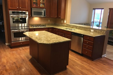 Example of a mid-sized trendy l-shaped open concept kitchen design in Philadelphia with a double-bowl sink, raised-panel cabinets, dark wood cabinets, granite countertops, brown backsplash, stainless steel appliances and an island