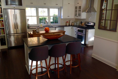 Mid-sized elegant dark wood floor kitchen photo in Other with an undermount sink, shaker cabinets, white cabinets, granite countertops, white backsplash, porcelain backsplash, stainless steel appliances and an island