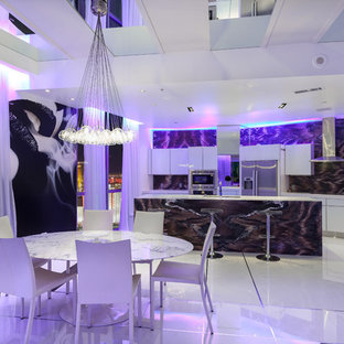 This is an example of a mid-sized contemporary single-wall eat-in kitchen in Las Vegas with an undermount sink, flat-panel cabinets, white cabinets, stone slab splashback, stainless steel appliances, porcelain floors and with island.