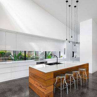 Design ideas for a mid-sized contemporary galley kitchen in Melbourne with flat-panel cabinets, white cabinets, marble benchtops, white splashback, concrete floors, with island, grey floor, white benchtop, a double-bowl sink, window splashback and stainless steel appliances.