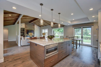 Huge transitional l-shaped medium tone wood floor and gray floor eat-in kitchen photo in San Francisco with flat-panel cabinets, dark wood cabinets, quartzite countertops, gray backsplash, glass tile backsplash, stainless steel appliances and an island