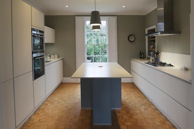 Design ideas for a medium sized contemporary galley kitchen in Devon with white cabinets, white splashback, glass sheet splashback and an island.