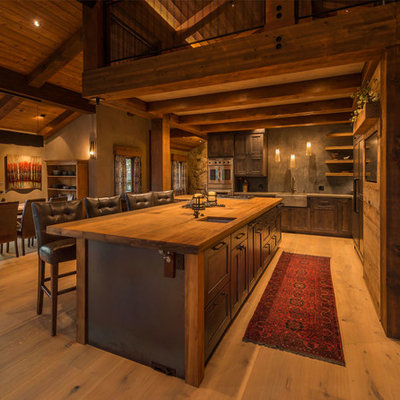 Eat-in kitchen - huge rustic l-shaped light wood floor eat-in kitchen idea in Other with a farmhouse sink, recessed-panel cabinets, wood countertops, gray backsplash, stainless steel appliances, an island and dark wood cabinets