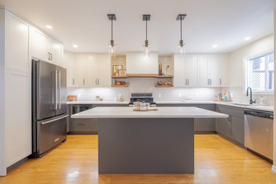 Example of a mid-sized cottage u-shaped medium tone wood floor and brown floor eat-in kitchen design in Calgary with an undermount sink, shaker cabinets, white cabinets, quartz countertops, gray backsplash, ceramic backsplash, stainless steel appliances, an island and white countertops