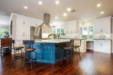 Inspiration for a large transitional u-shaped medium tone wood floor open concept kitchen remodel in Los Angeles with an island, shaker cabinets, white cabinets, white backsplash, subway tile backsplash, stainless steel appliances, a double-bowl sink and quartzite countertops