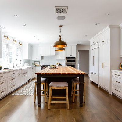 Inspiration for a mid-sized country l-shaped medium tone wood floor and brown floor kitchen remodel in Los Angeles with a farmhouse sink, shaker cabinets, white cabinets, quartz countertops, white backsplash, subway tile backsplash, stainless steel appliances, an island and white countertops