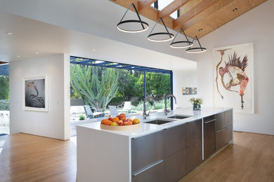 Example of a mid-sized minimalist l-shaped light wood floor and beige floor eat-in kitchen design in Los Angeles with a drop-in sink, stainless steel appliances, an island, white countertops, flat-panel cabinets, stainless steel cabinets and marble countertops